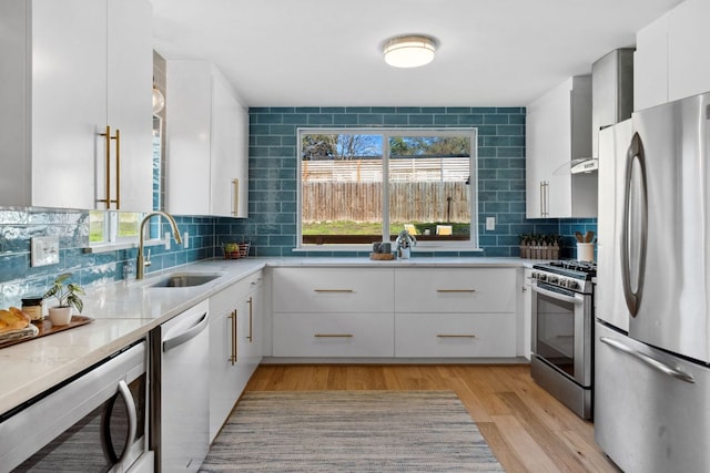 kitchen with tasteful backsplash, stainless steel appliances, light countertops, light wood-style floors, and a sink