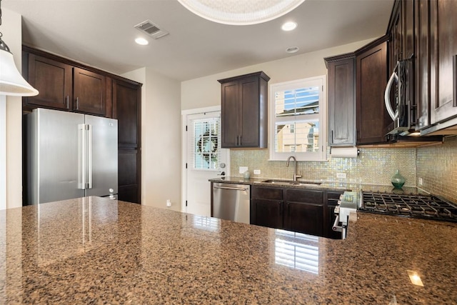 kitchen featuring appliances with stainless steel finishes, visible vents, a sink, and dark brown cabinetry