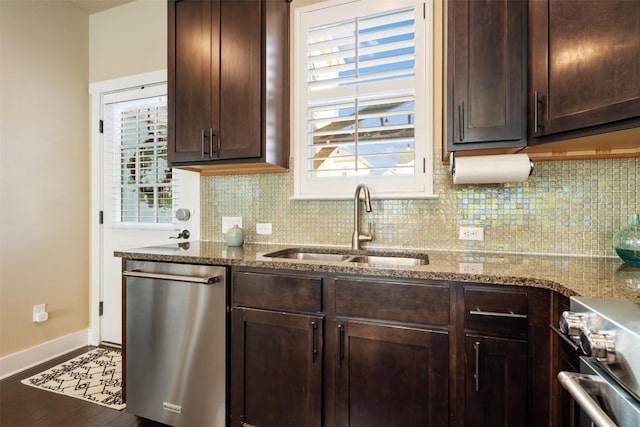 kitchen featuring tasteful backsplash, appliances with stainless steel finishes, stone countertops, a sink, and dark brown cabinets