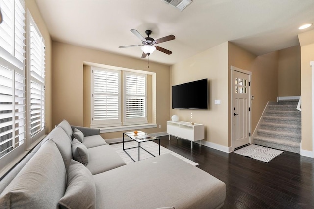 living area with wood finished floors, a ceiling fan, visible vents, baseboards, and stairway