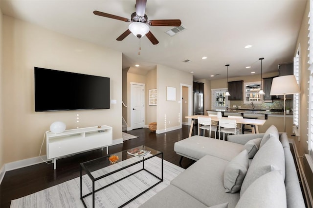 living area with dark wood-type flooring, visible vents, and baseboards