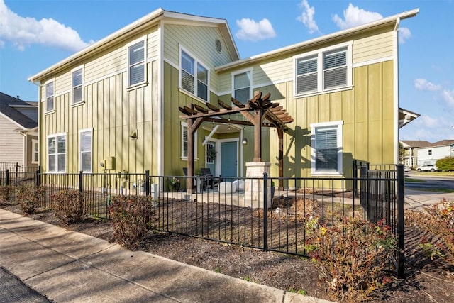 view of front of house featuring board and batten siding, fence, and a pergola