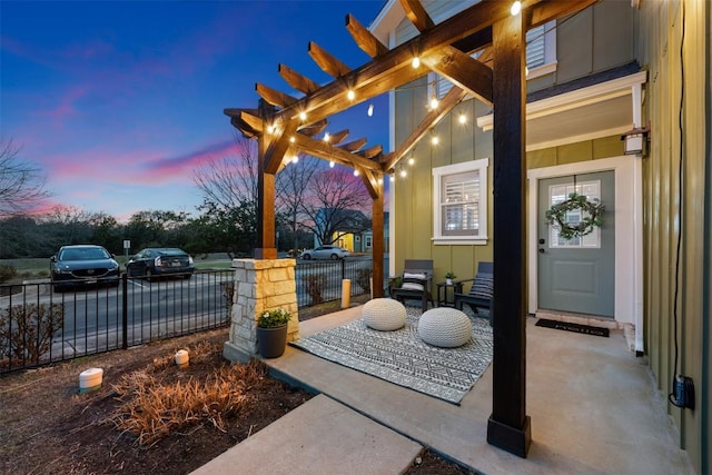 patio terrace at dusk featuring fence and a pergola