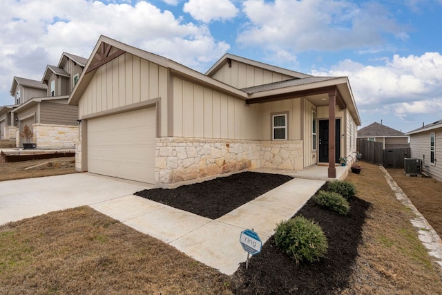 view of front of house with concrete driveway, stone siding, an attached garage, cooling unit, and board and batten siding