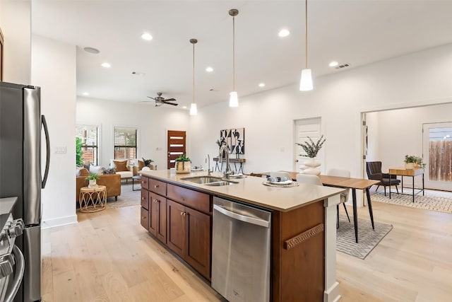 kitchen featuring light wood-style flooring, appliances with stainless steel finishes, open floor plan, and a sink