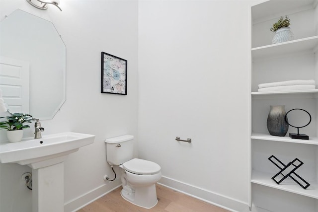 bathroom with a sink, wood finished floors, toilet, and baseboards