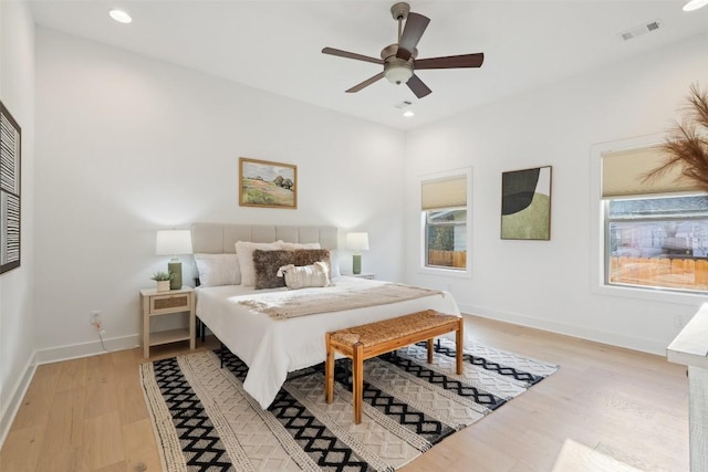 bedroom with light wood-style flooring, multiple windows, visible vents, and baseboards