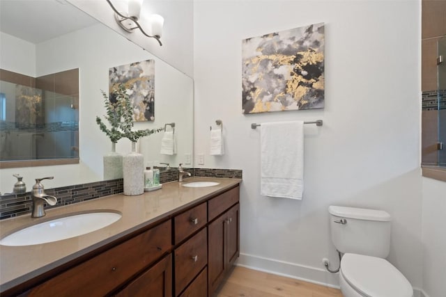 full bathroom with a sink, a tile shower, toilet, and double vanity