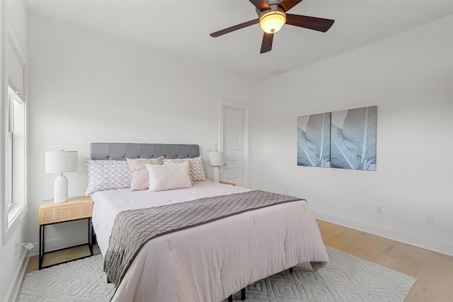 bedroom featuring a ceiling fan, baseboards, and wood finished floors