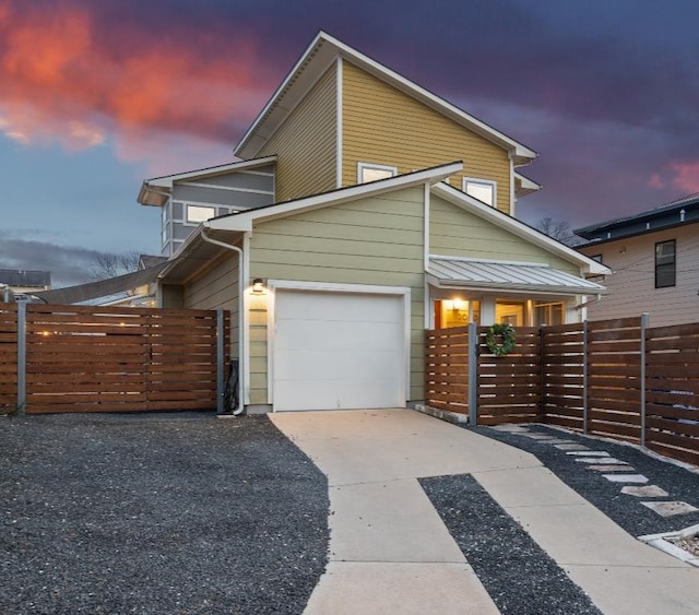 contemporary house featuring a garage, driveway, and fence