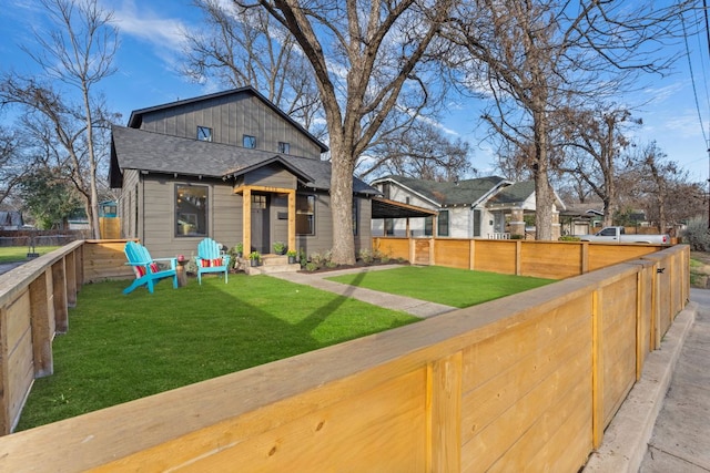 view of front of property with a shingled roof, fence private yard, and a front lawn