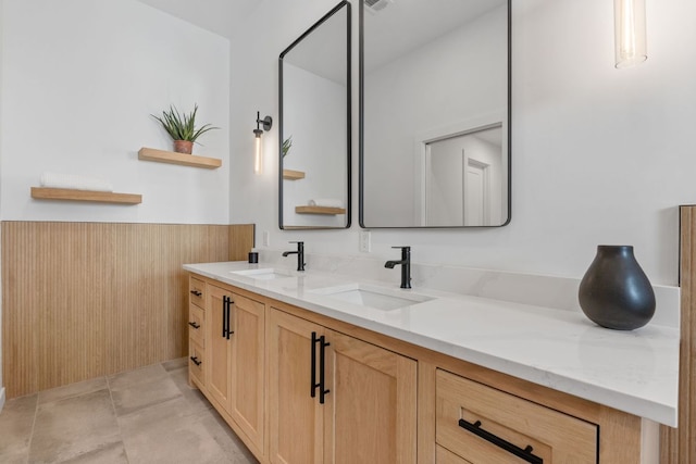 full bathroom featuring tile patterned flooring, wainscoting, a sink, and double vanity