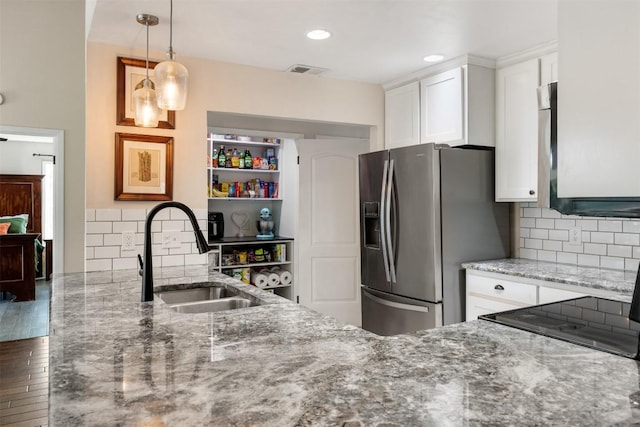 kitchen with visible vents, white cabinets, a sink, light stone countertops, and stainless steel fridge with ice dispenser