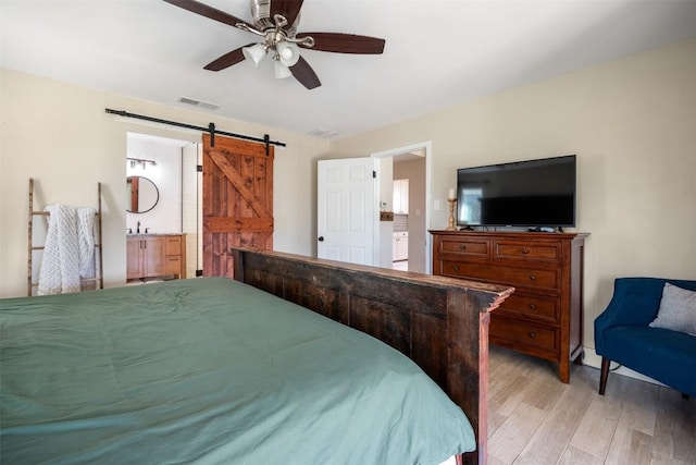 bedroom with ceiling fan, a barn door, a sink, visible vents, and light wood finished floors