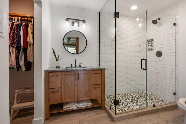 full bath with toilet, wood finished floors, a spacious closet, vanity, and a shower stall