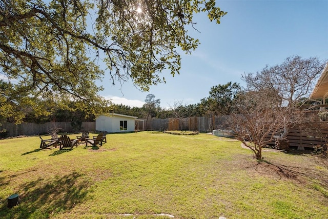 view of yard featuring an outdoor fire pit, a fenced backyard, and an outdoor structure