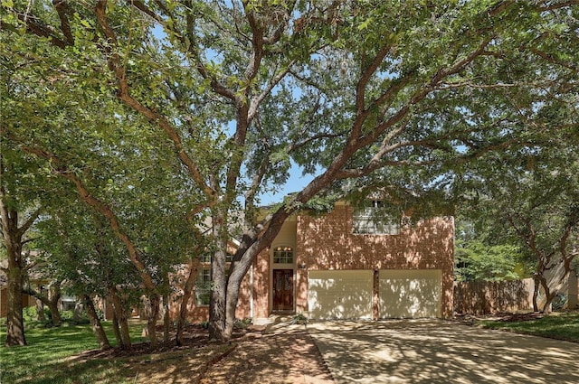 view of front of home with concrete driveway, brick siding, and an attached garage