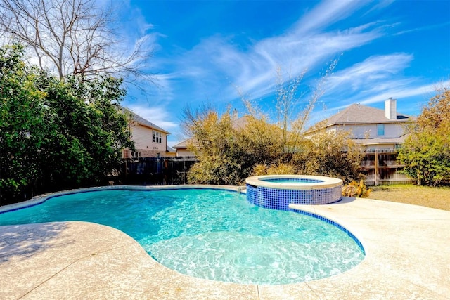 view of pool with a patio area, a pool with connected hot tub, and fence