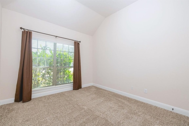 carpeted empty room with vaulted ceiling and baseboards