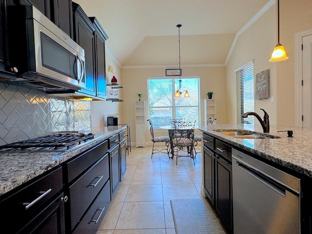 kitchen featuring stainless steel appliances, lofted ceiling, tasteful backsplash, a sink, and dark cabinetry