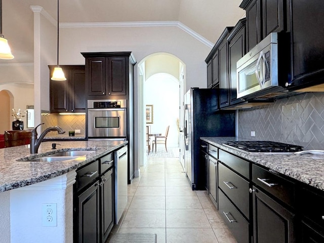 kitchen featuring arched walkways, light tile patterned floors, appliances with stainless steel finishes, ornamental molding, and a sink