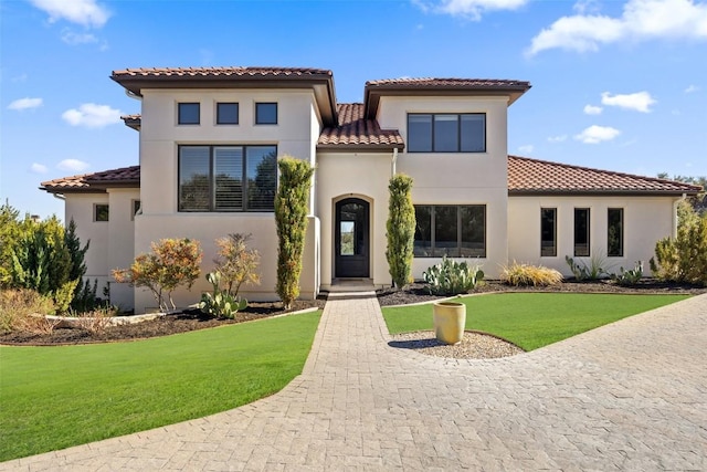 mediterranean / spanish-style home with a front lawn, a tile roof, and stucco siding