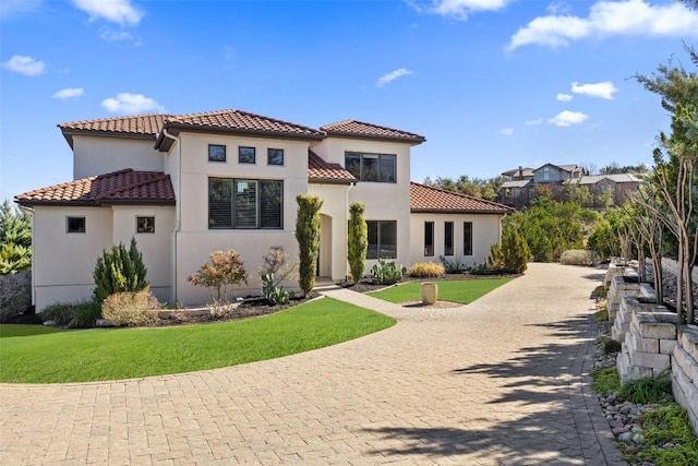 view of front of house featuring a tile roof, a front yard, and stucco siding