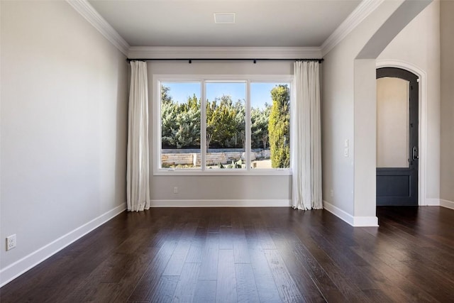 spare room with baseboards, crown molding, arched walkways, and wood finished floors