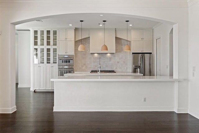 kitchen with dark wood-style flooring, stainless steel appliances, light countertops, decorative backsplash, and a sink