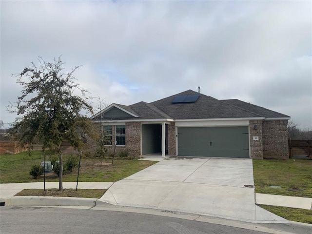 ranch-style home with a garage, brick siding, a front lawn, and roof mounted solar panels