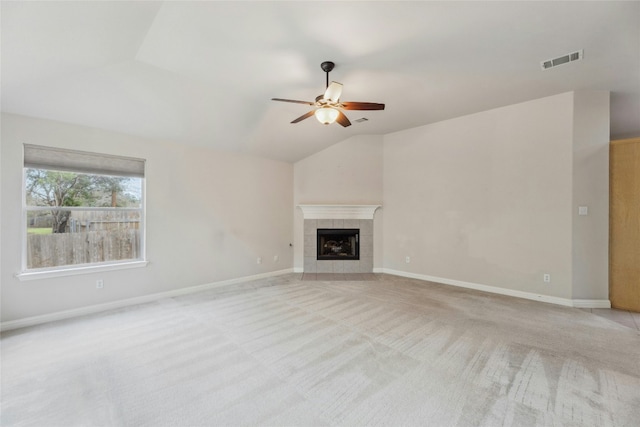 unfurnished living room featuring lofted ceiling, light colored carpet, a ceiling fan, visible vents, and a tiled fireplace