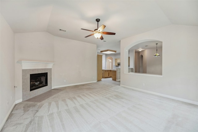 unfurnished living room with vaulted ceiling, visible vents, a fireplace, and light carpet