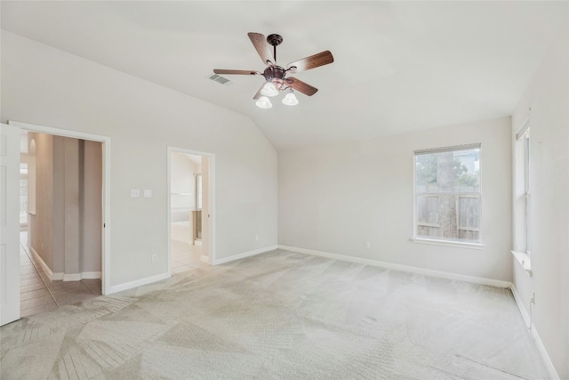 unfurnished bedroom featuring connected bathroom, light colored carpet, visible vents, baseboards, and vaulted ceiling