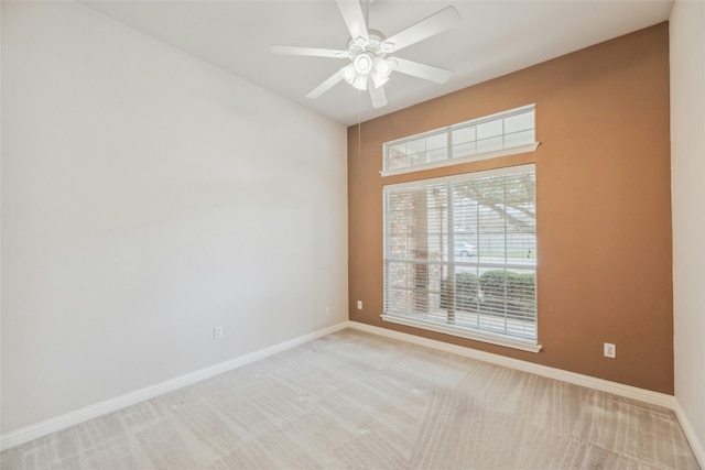 spare room featuring a ceiling fan, light colored carpet, and baseboards