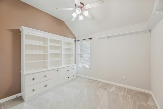 unfurnished bedroom featuring lofted ceiling, baseboards, a ceiling fan, and light colored carpet