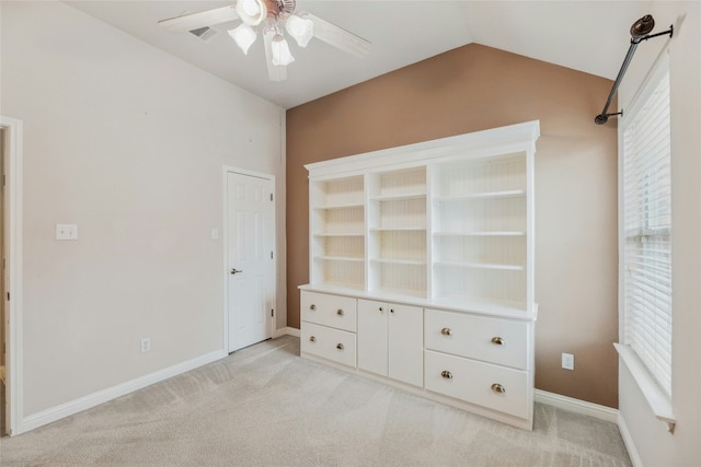 unfurnished bedroom featuring light carpet, multiple windows, baseboards, and vaulted ceiling