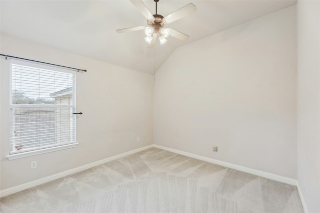 empty room with a ceiling fan, lofted ceiling, light colored carpet, and baseboards