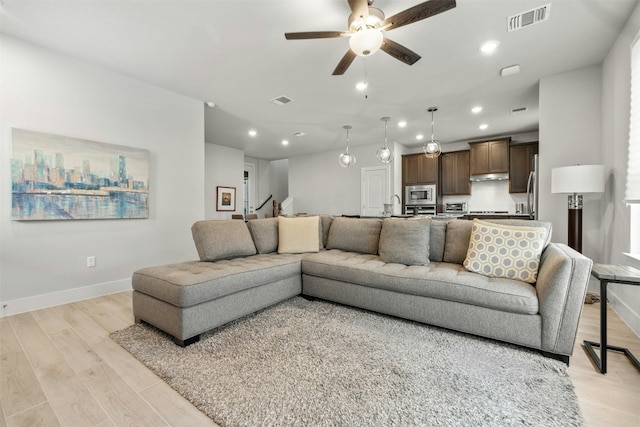 living area with light wood-style flooring, visible vents, baseboards, and recessed lighting