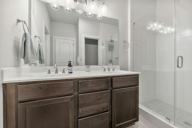 full bath featuring double vanity, a sink, and a shower stall