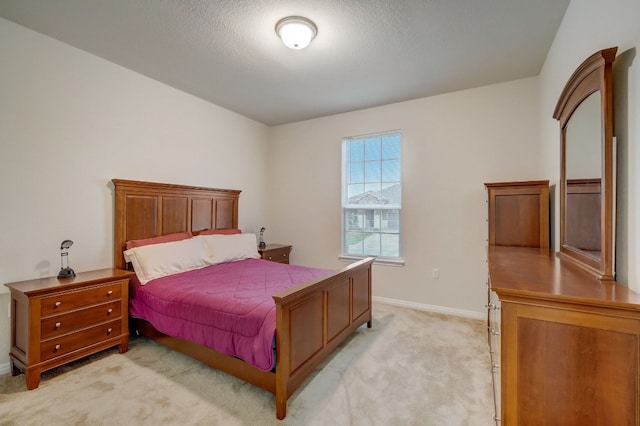 bedroom featuring baseboards, a textured ceiling, and light colored carpet