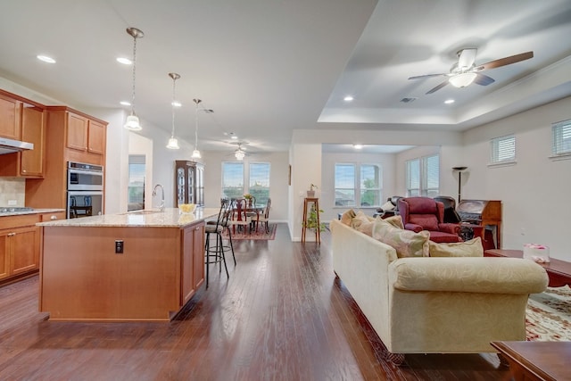 living area featuring ceiling fan, dark wood-type flooring, a raised ceiling, and recessed lighting