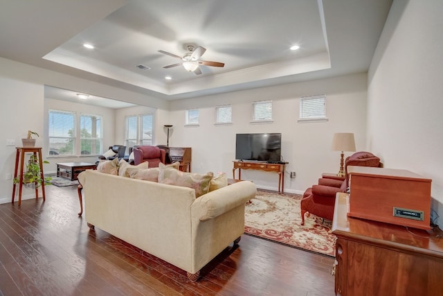 living room with dark wood-type flooring, a tray ceiling, and visible vents