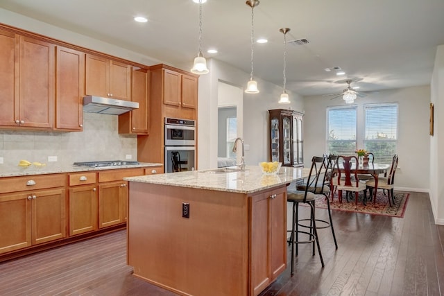 kitchen with tasteful backsplash, visible vents, appliances with stainless steel finishes, under cabinet range hood, and a sink