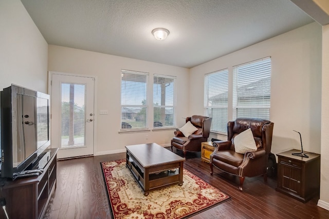 living area with a textured ceiling, dark wood finished floors, and baseboards