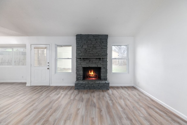 unfurnished living room with a stone fireplace, light wood-type flooring, and baseboards