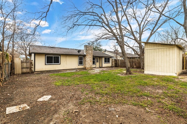 rear view of property featuring a patio, a fenced backyard, a chimney, an outbuilding, and a storage unit