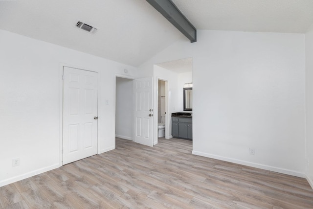 unfurnished room featuring baseboards, visible vents, lofted ceiling with beams, and light wood finished floors