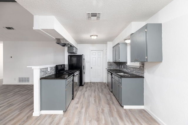 kitchen featuring gray cabinetry, visible vents, appliances with stainless steel finishes, decorative backsplash, and dark countertops