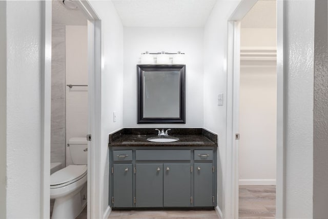 full bath featuring baseboards, toilet, wood finished floors, a textured ceiling, and vanity