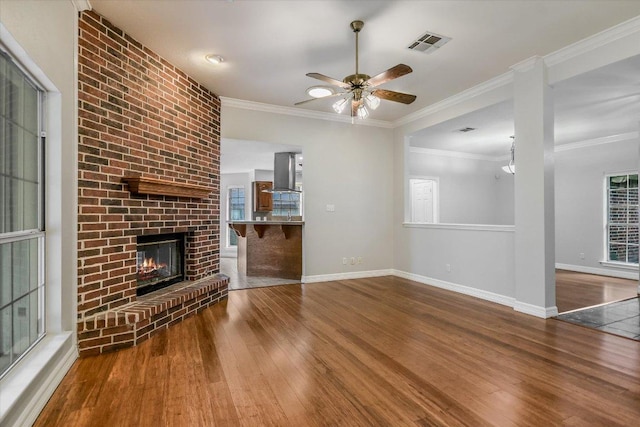 503 Riverview Dr, Georgetown, TX 78628 - unfurnished living room featuring wood finished floors, ceiling fan, ornamental molding, and a brick fireplace